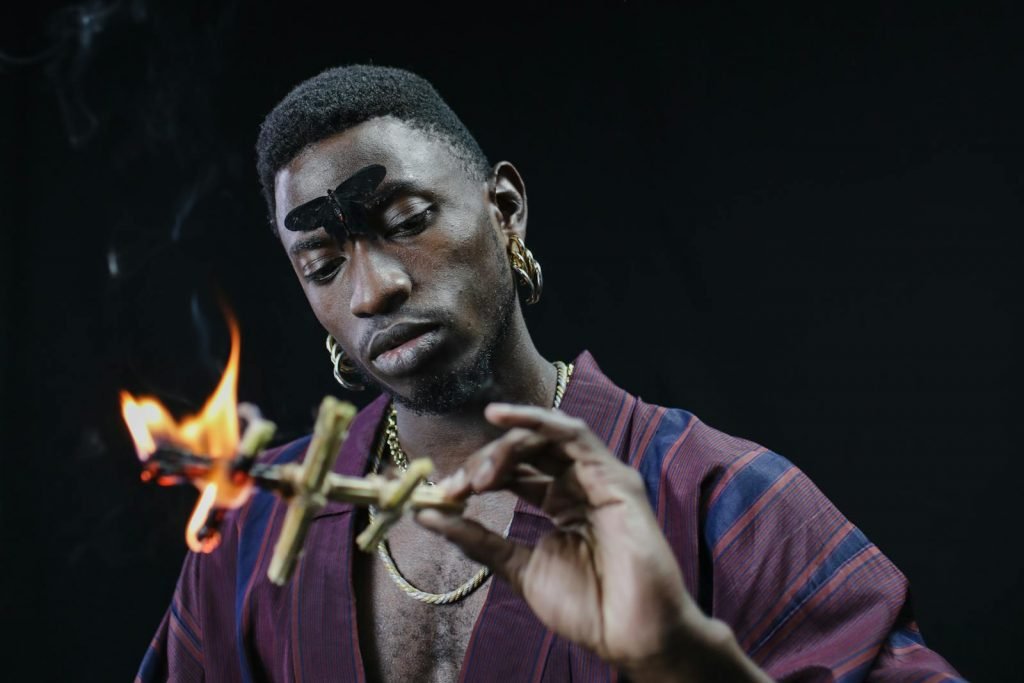 A Man in Maroon Robe Holding a Burning Stick voodoo hoodoo