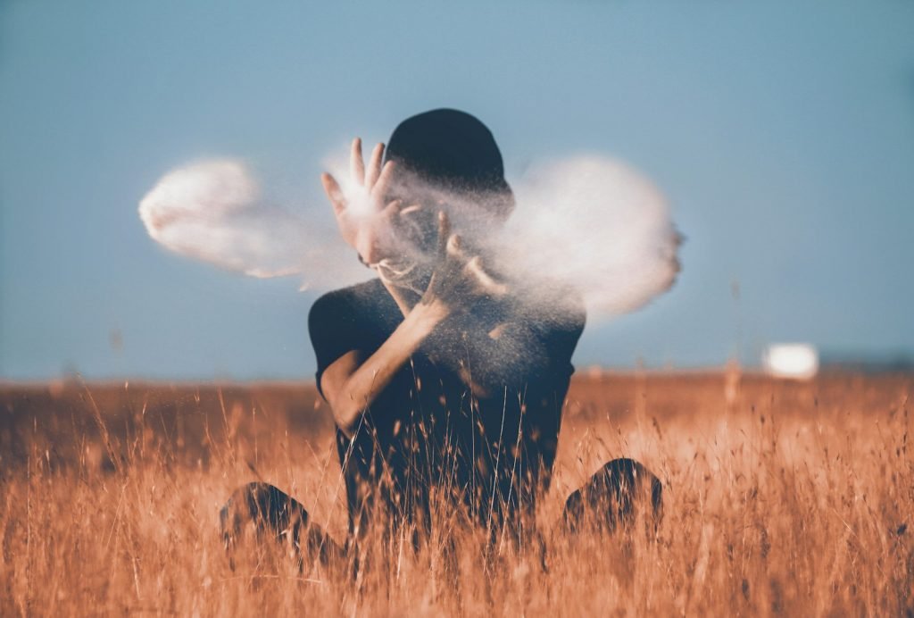 man sitting on brown grass field playing with smoke Chaos Magic